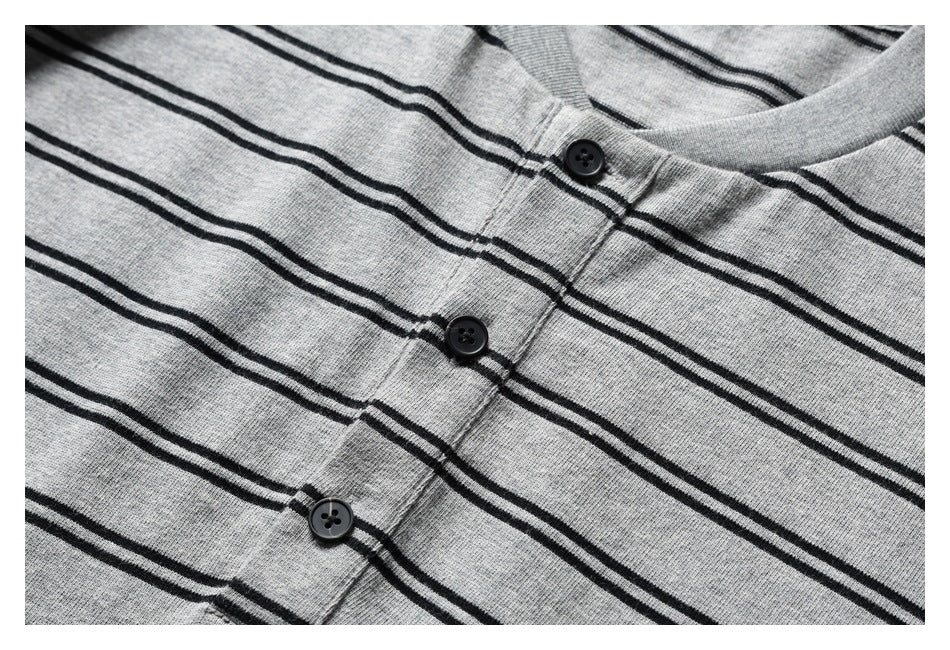 Close-up of a gray knit shirt with thin black stripes, showing its black buttons and placket.
