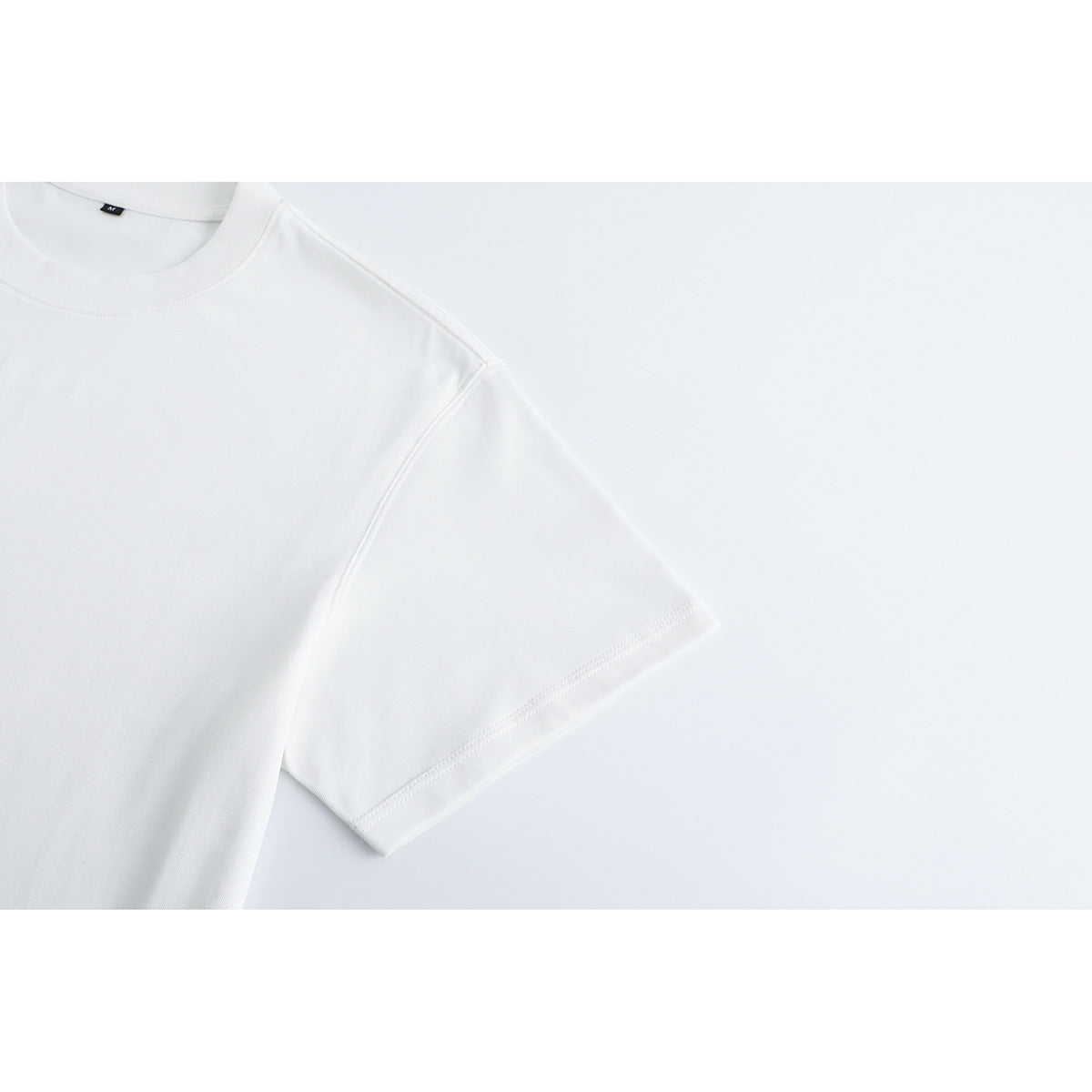 Close-up of a plain white T-shirt sleeve and shoulder seam.