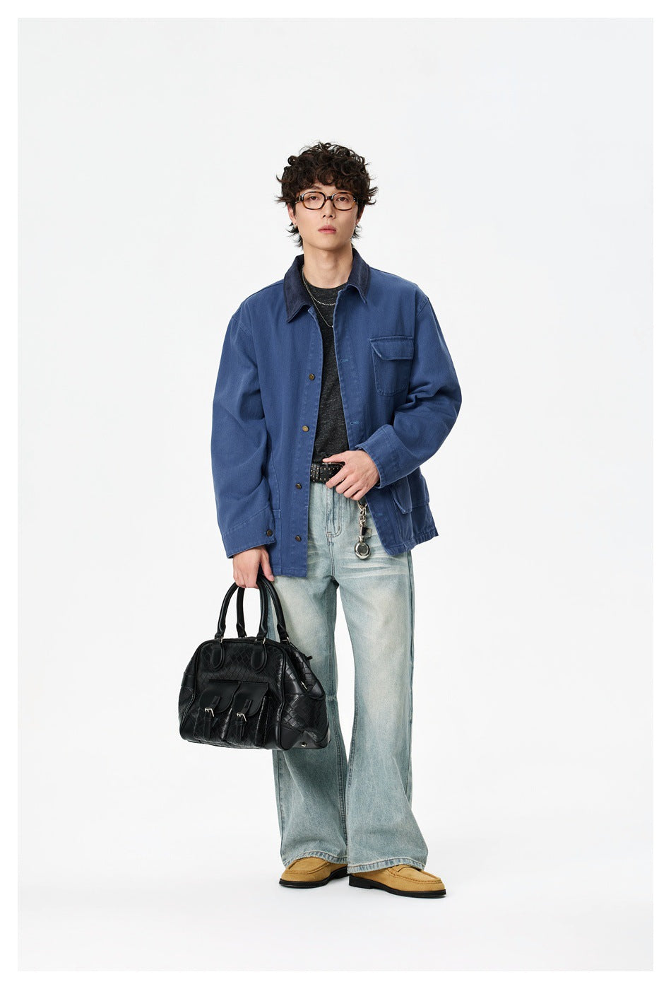 Front view of a model wearing a blue work jacket with a dark collar, chest pocket, and light-wash jeans.