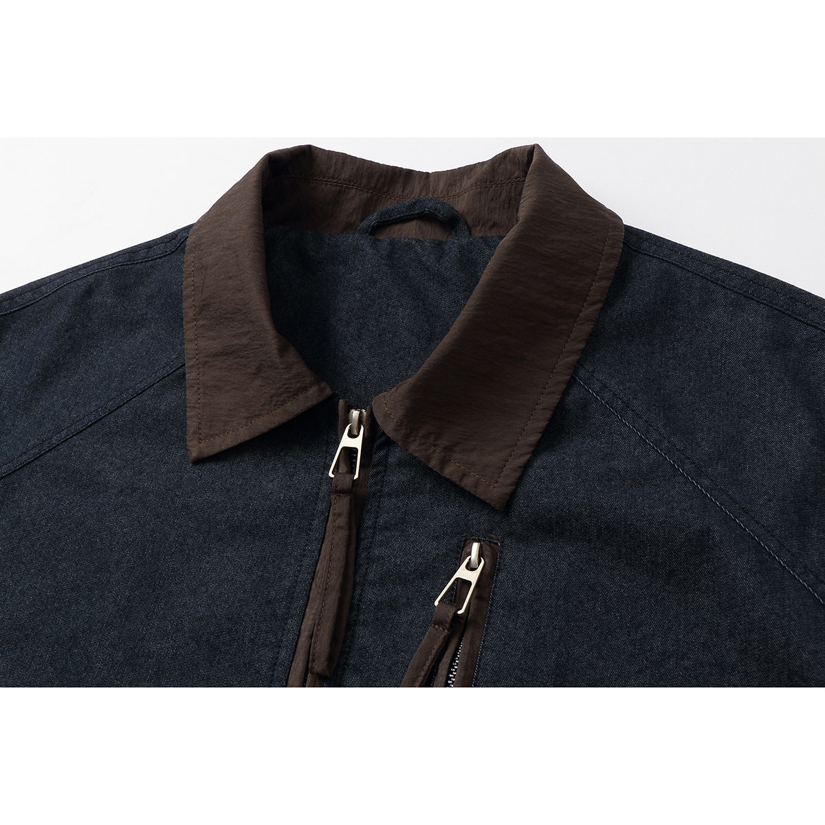 Close-up of a dark indigo jacket with a brown collar, front zipper, and chest zip pocket.