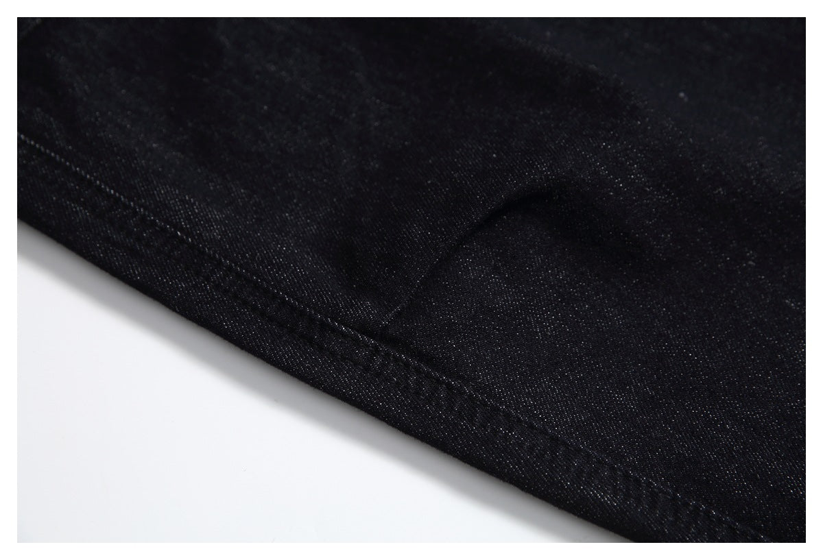 Close-up of black denim with a diagonal stitched seam and fabric texture.