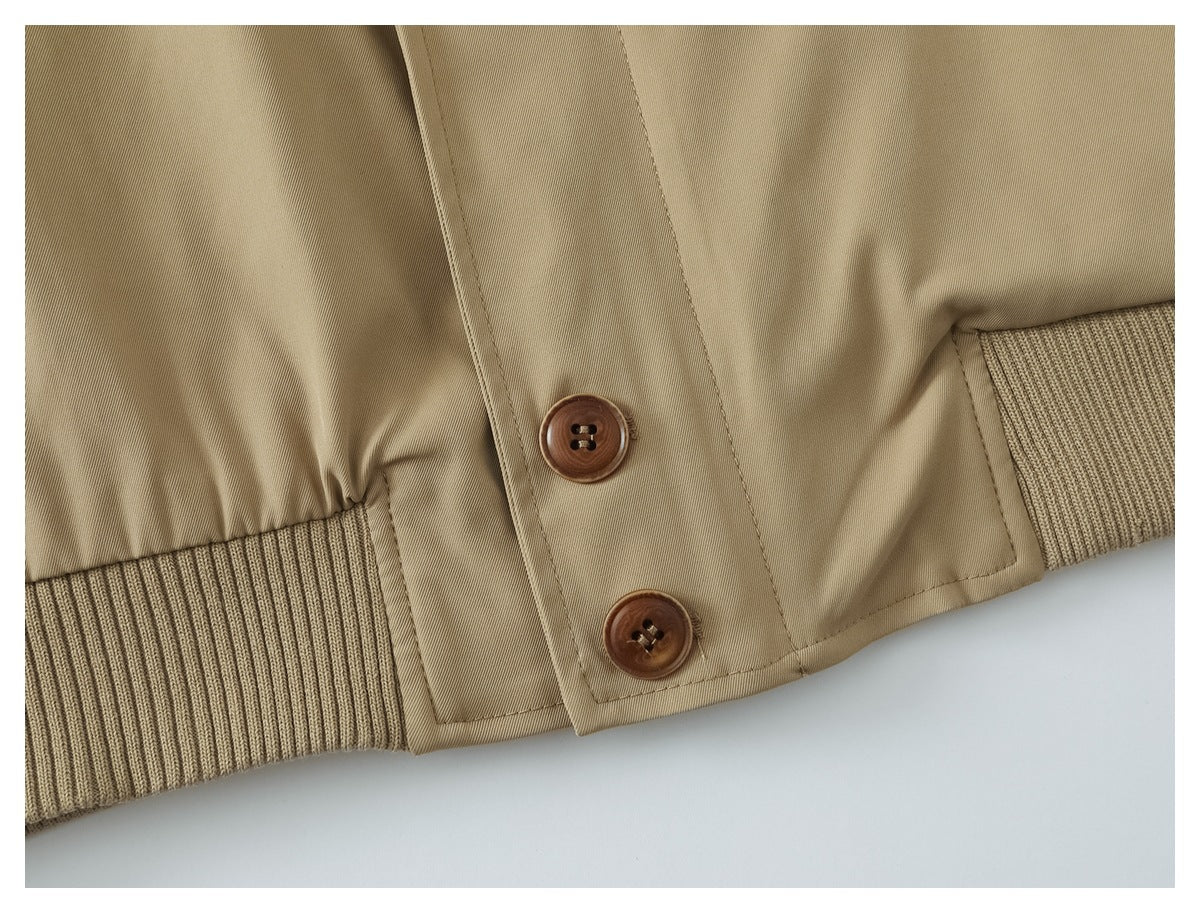 Close-up of two brown buttons on the tan jacket, with a ribbed hem band.