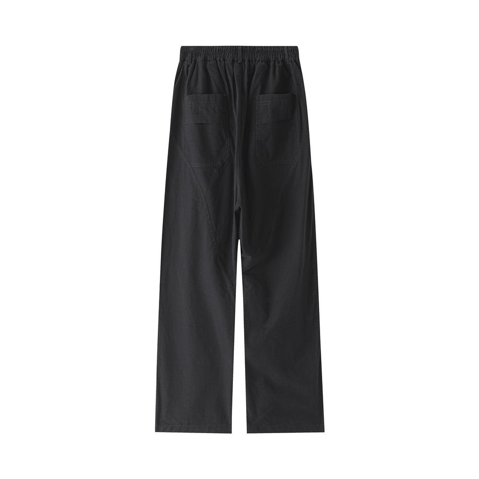 Back view of black wide-leg trousers with an elasticated waistband, two patch pockets, and curved leg seams.