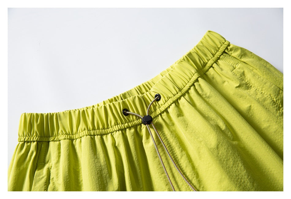 Close-up of neon yellow shorts showing the gathered elastic waistband and adjustable drawcord.