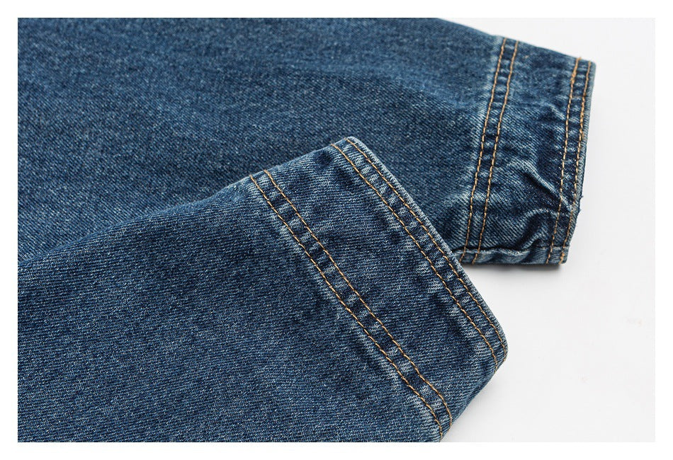 Close-up of blue denim sleeve ends with folded cuffs and contrasting tan stitching.