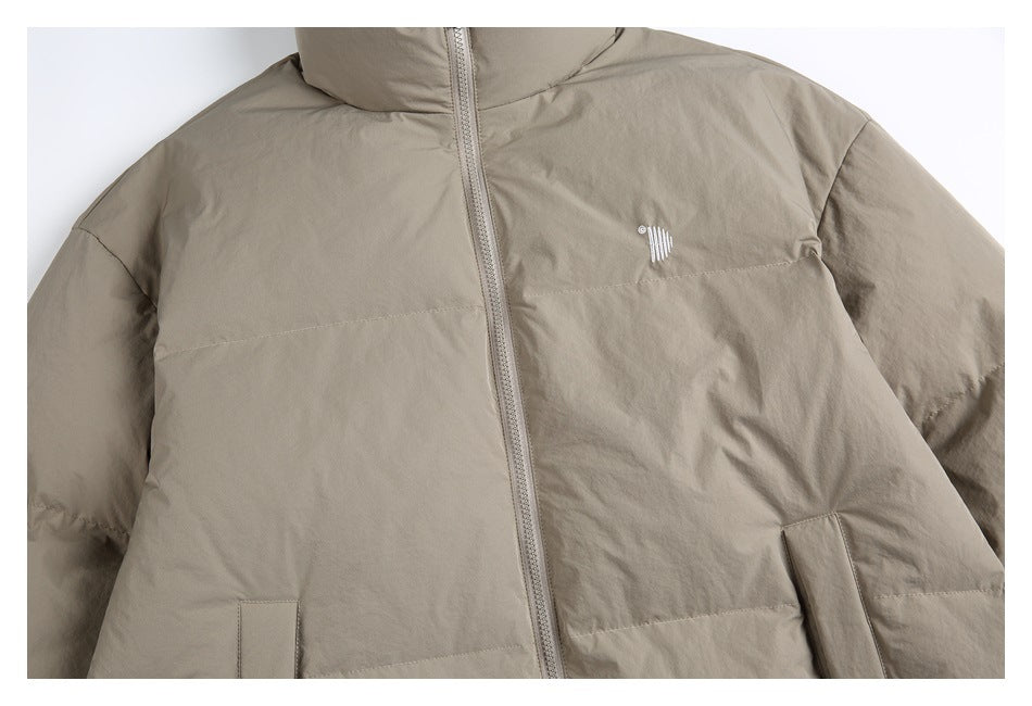 Cropped front view of a taupe padded jacket with a high collar, zipper, chest mark, and pockets.