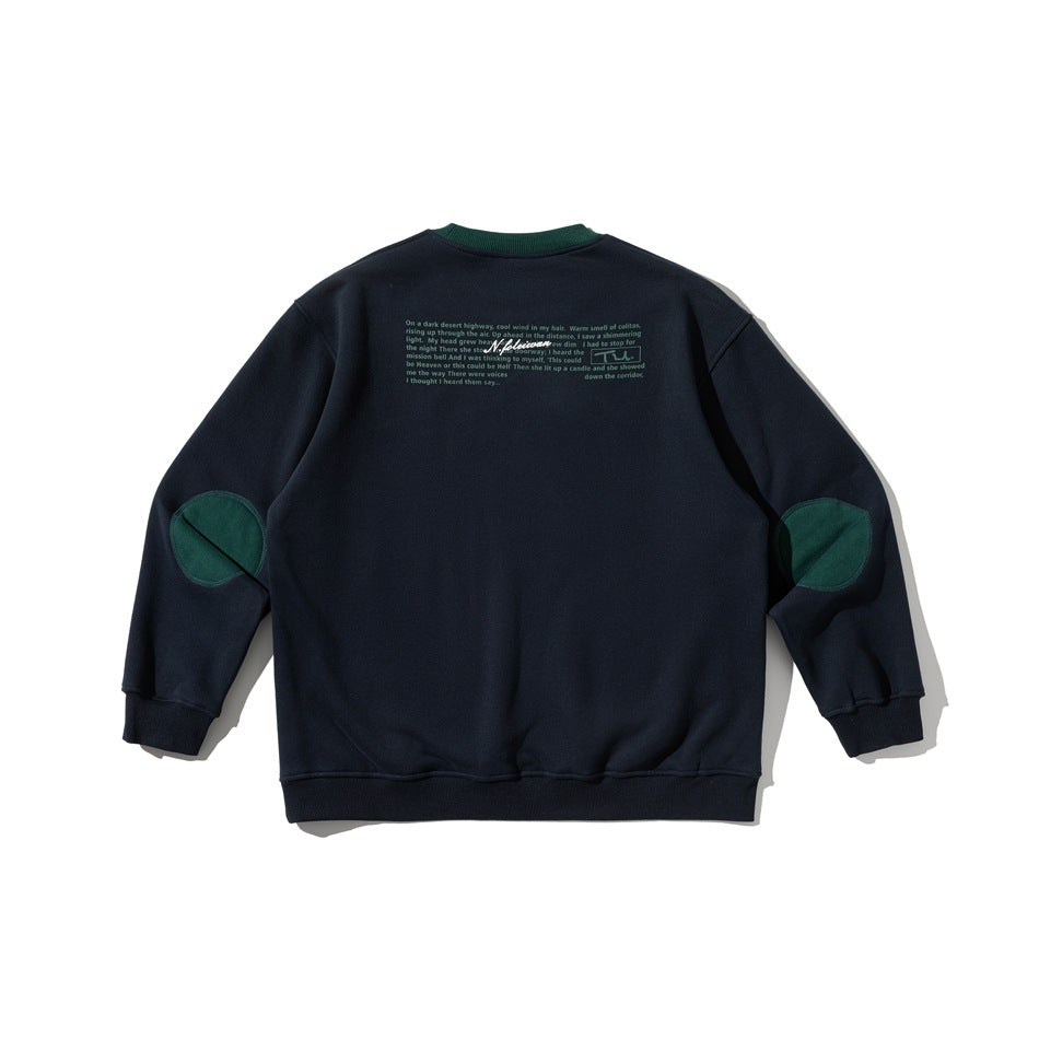 Back of a navy crewneck sweatshirt with green collar trim, green elbow patches, and small text across the upper back.