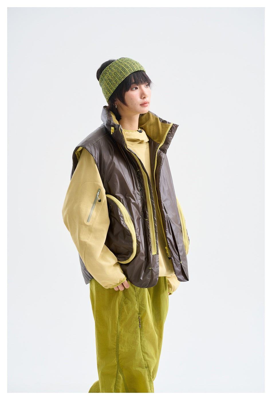 Model in a dark brown sleeveless vest with yellow-edged pockets, shown at a three-quarter angle.