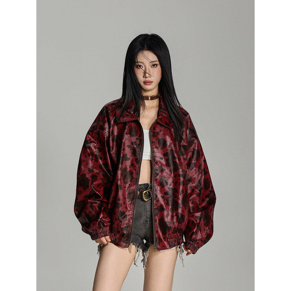 Model wearing an oversized burgundy jacket with a dark mottled pattern, zip front, pointed collar and elastic cuffs.