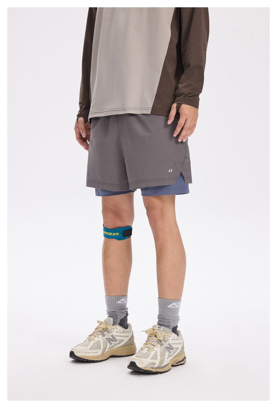 Front view of a model wearing layered gray running shorts over blue-gray compression shorts.