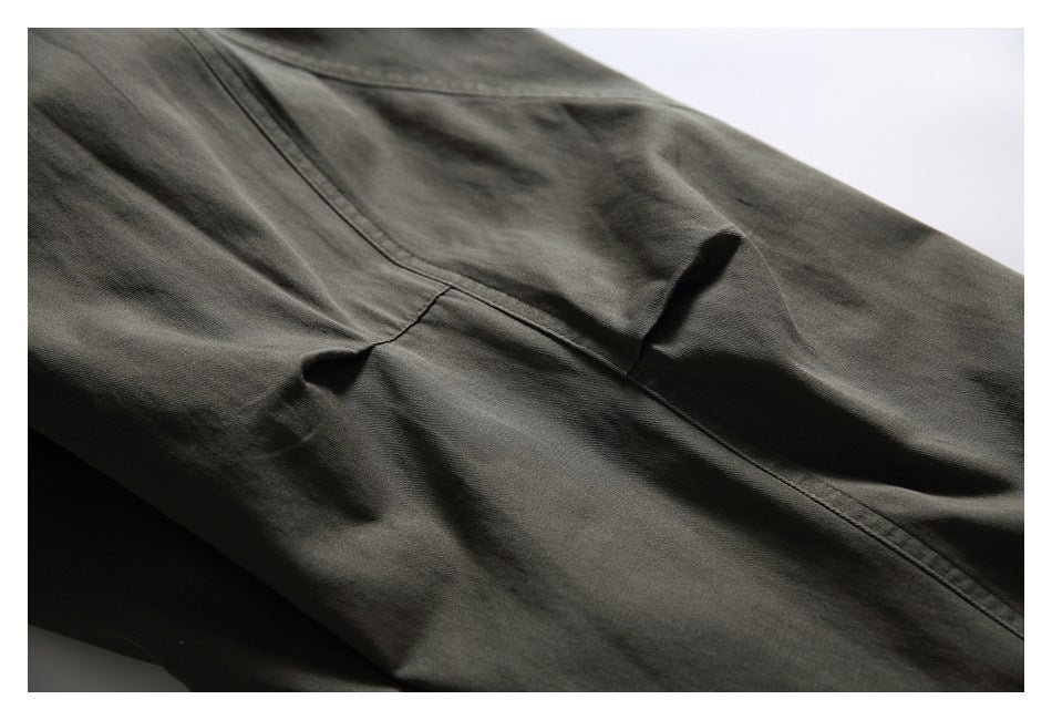 Close-up of dark olive pants showing a curved panel seam and folded fabric.