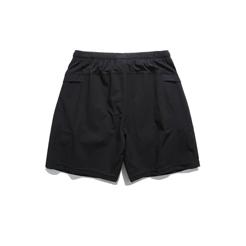 Back view of black shorts with elastic waistband and paneled seams on the hips and thighs