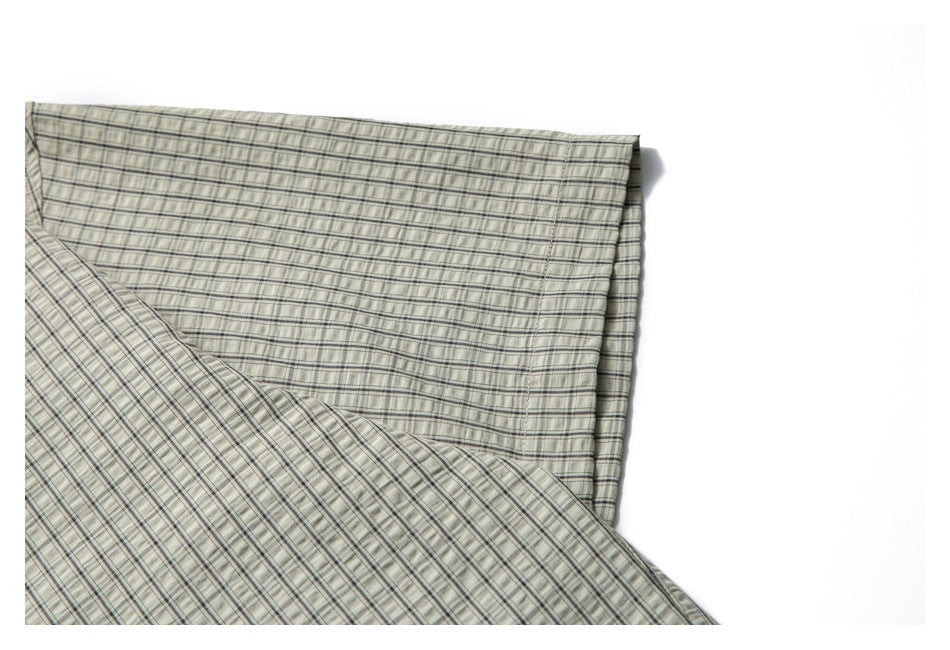 Close-up of the pale gray-green plaid shirt hem and overlapping fabric.