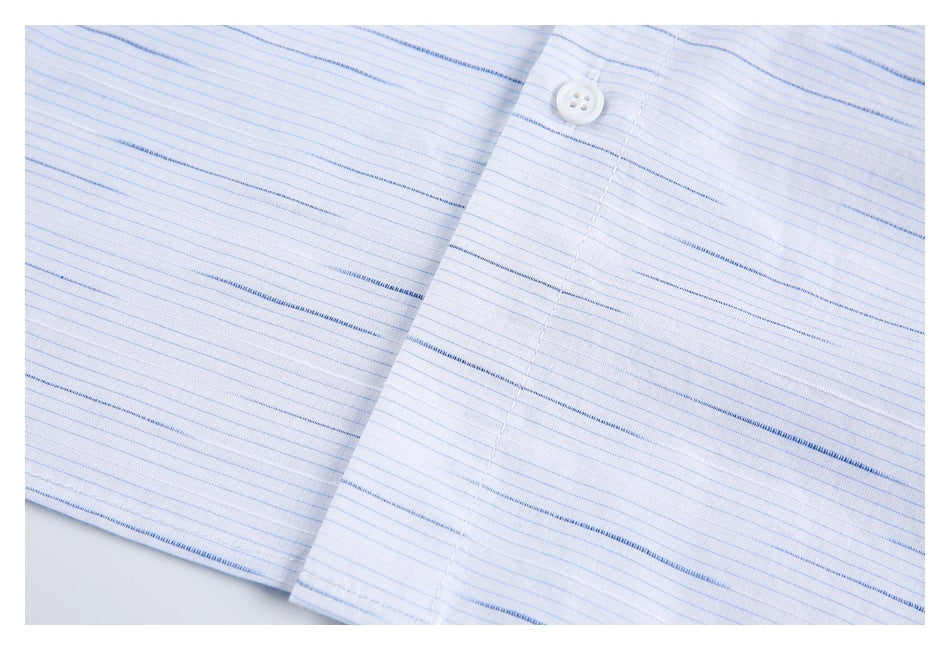 Close-up of a white shirt's button placket with fine blue stripes and a white button.