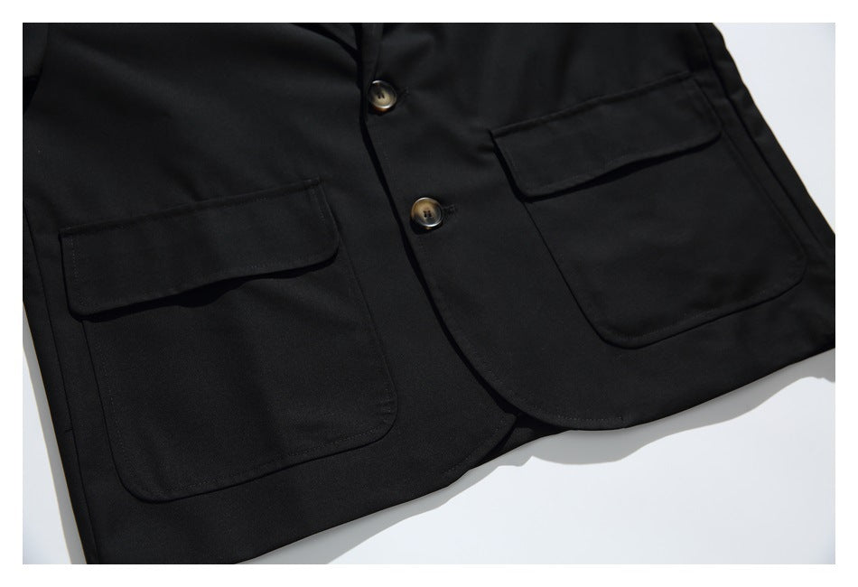 Close view of the black blazer's two flap pockets, front buttons, and rounded lower edges.