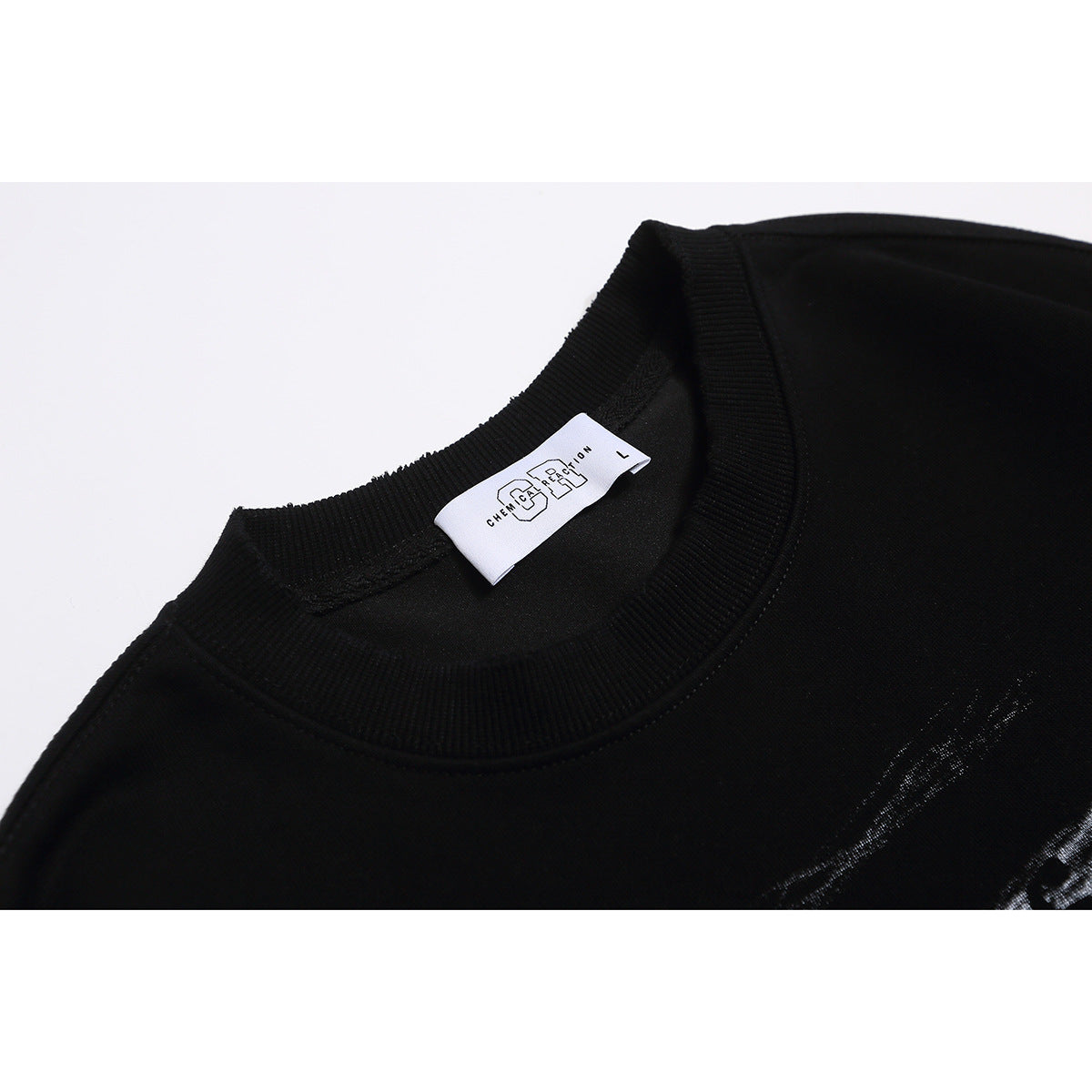 Close-up of a black sweatshirt's ribbed crew neck, white size label and partial pale chest print.