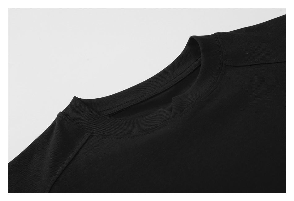 Close-up of the black T-shirt's crew neckline, collar stitching, and shoulder seam.