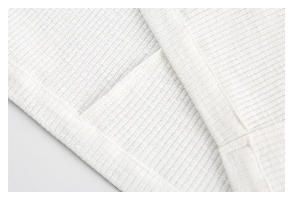 Close-up of overlapping stitched panels on the off-white ribbed top.