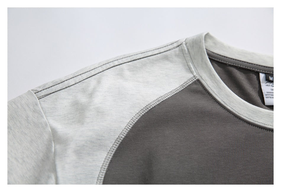 Close-up of the crew neckline and shoulder of a charcoal shirt with light gray panels and visible stitching.