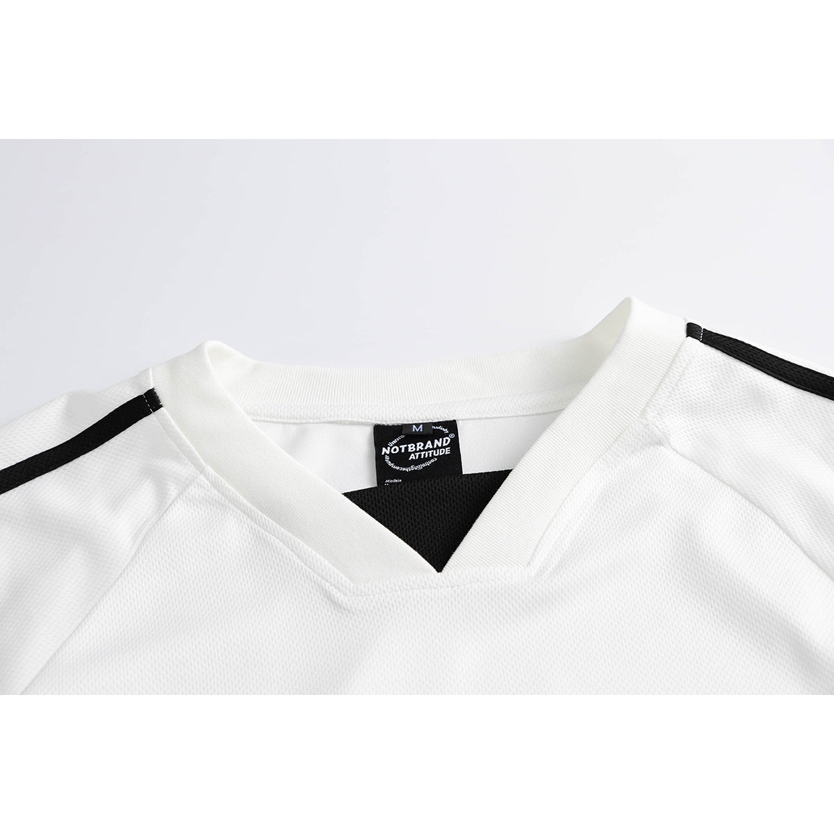 Close-up of a white V-neck jersey with black shoulder stripes and a black neck label.