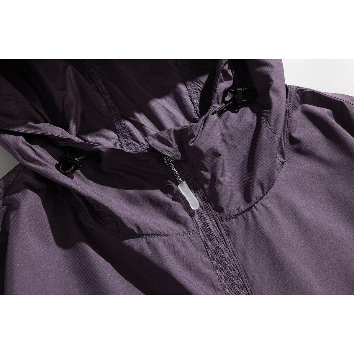 Close-up of a purple jacket hood with black adjustment toggles and a central zipper.