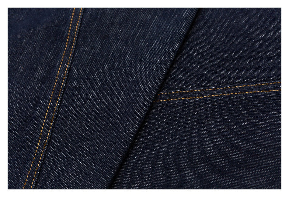 Close-up of dark indigo denim panels with contrasting golden-orange double-stitched seams.