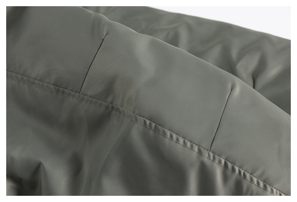 Close-up of olive-gray jacket panels and a stitched seam, with black quilted lining visible behind.