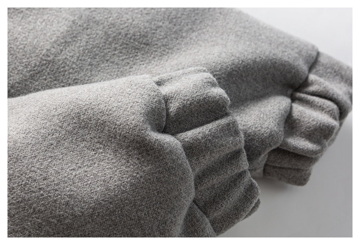 Close-up of folded gray mottled fabric with layered, gathered garment edges.