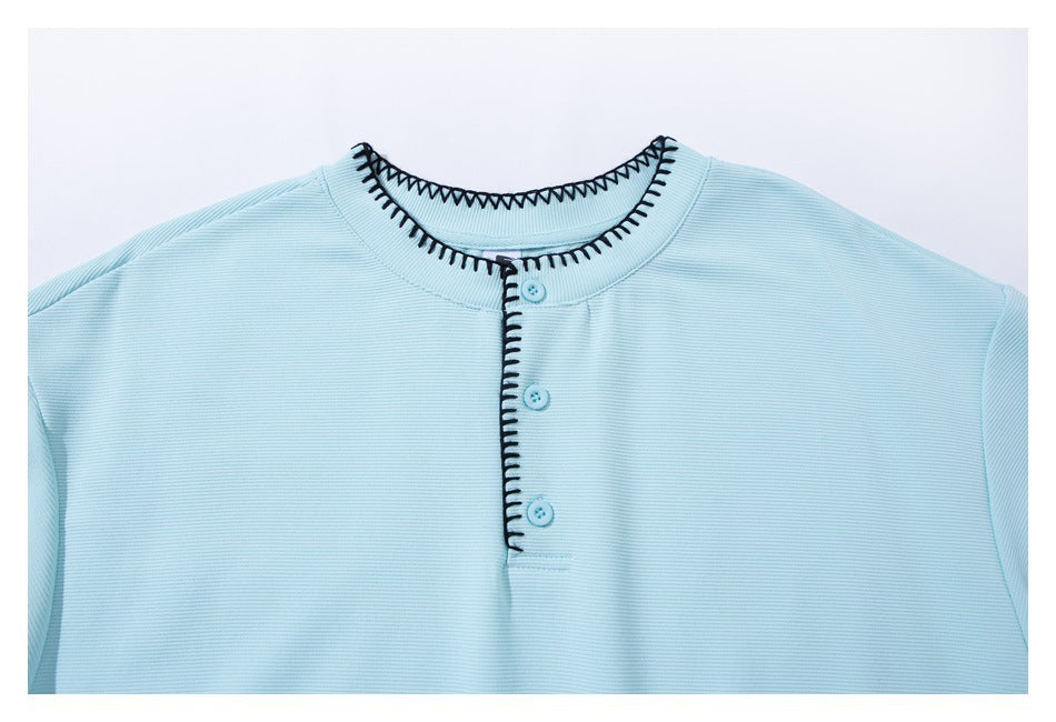 Close-up of a light blue ribbed shirt collar and three-button placket with black zigzag stitching.