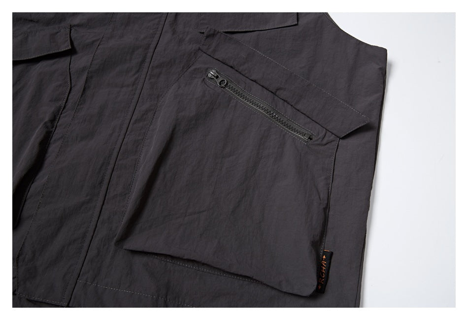 Close-up of a dark charcoal garment pocket with an angled zipper and a small sewn-on label.