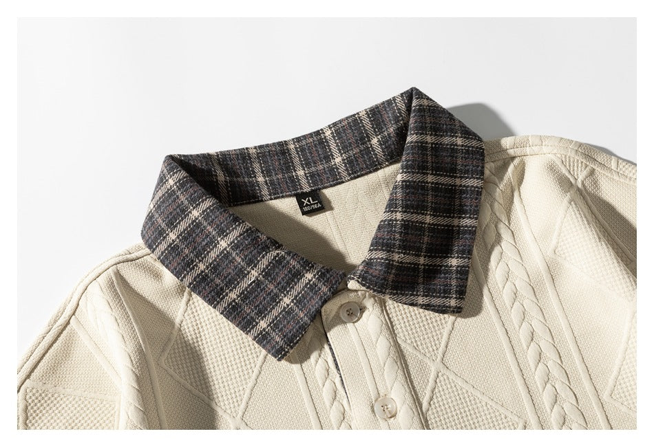 Close-up of a cream sweater with a dark plaid collar, button placket, and textured geometric knit.