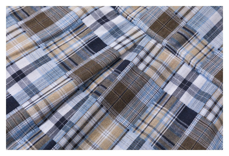 Close-up of the blue, navy, brown, and white plaid shirt fabric and stitched seam.