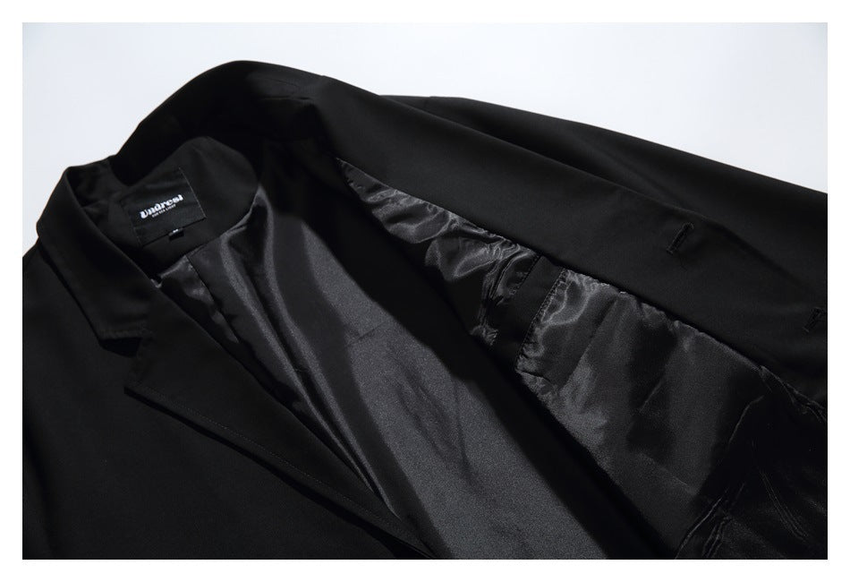 Black blazer opened to show its shiny dark lining and sewn-in neck label.