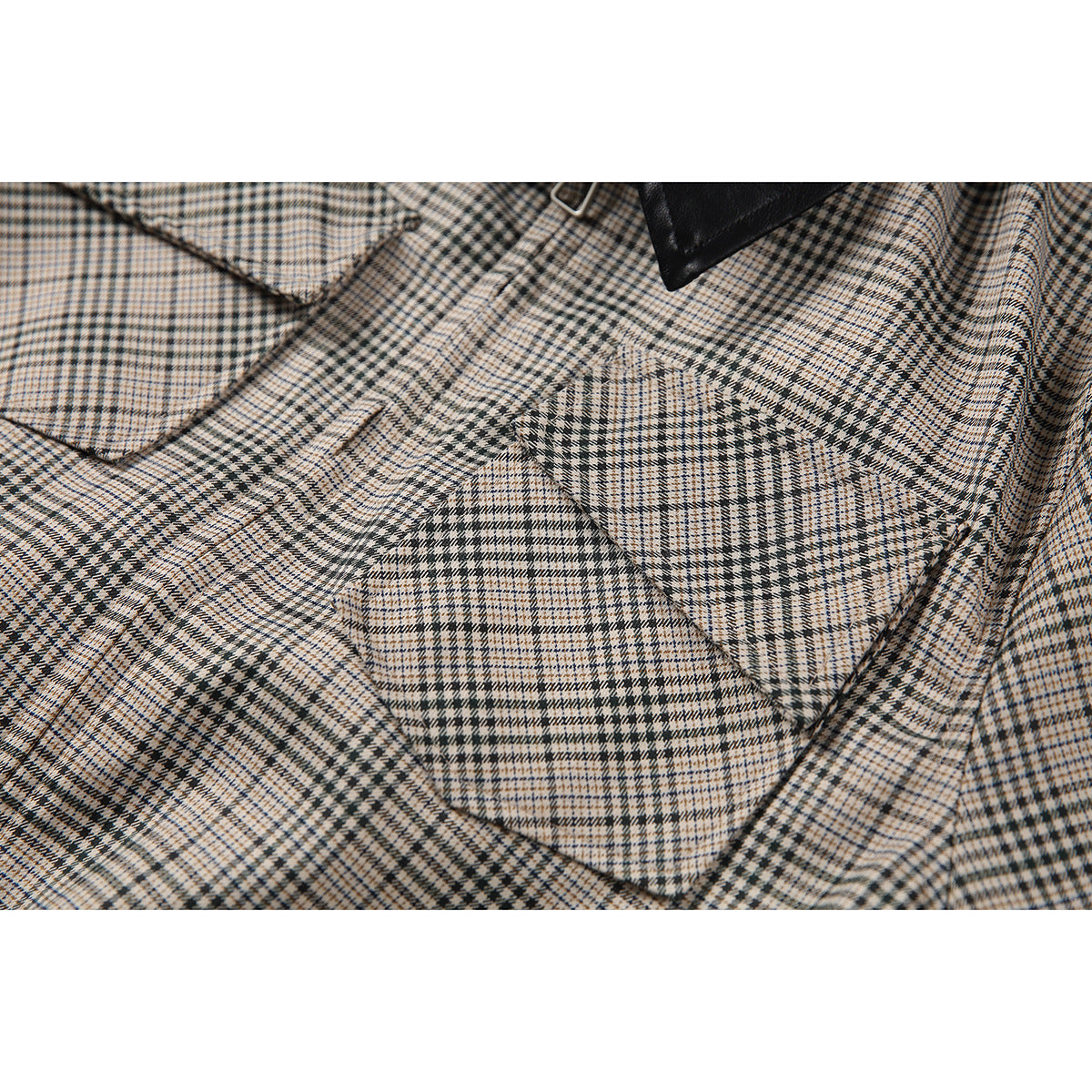 Close-up of a flap chest pocket on a beige and dark plaid shirt, showing the intersecting checks and stitching.
