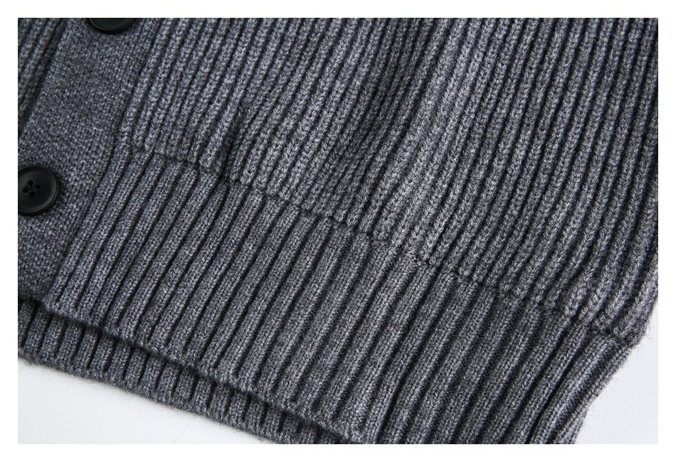 Close-up of charcoal gray ribbed knit fabric, a black button, and the ribbed hem.