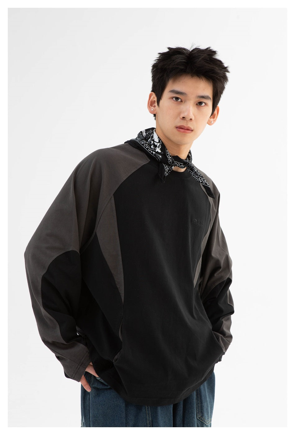 Model wearing a black long-sleeve raglan shirt with charcoal panels and a black-and-white neck scarf.