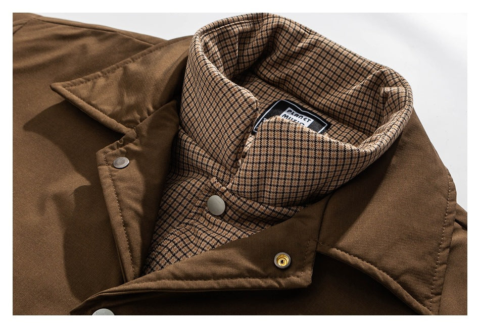 Close view of a brown jacket's front opening, metal snaps, and tan-and-black checked inner collar.