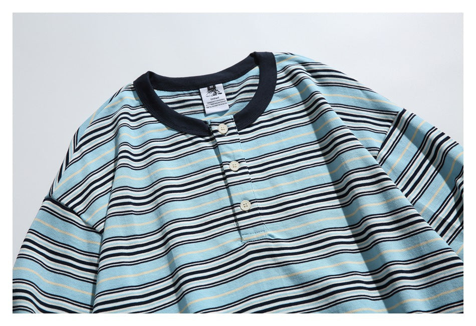 Close-up of a light blue, navy, and white striped henley showing its dark collar, three-button placket, and neck label.