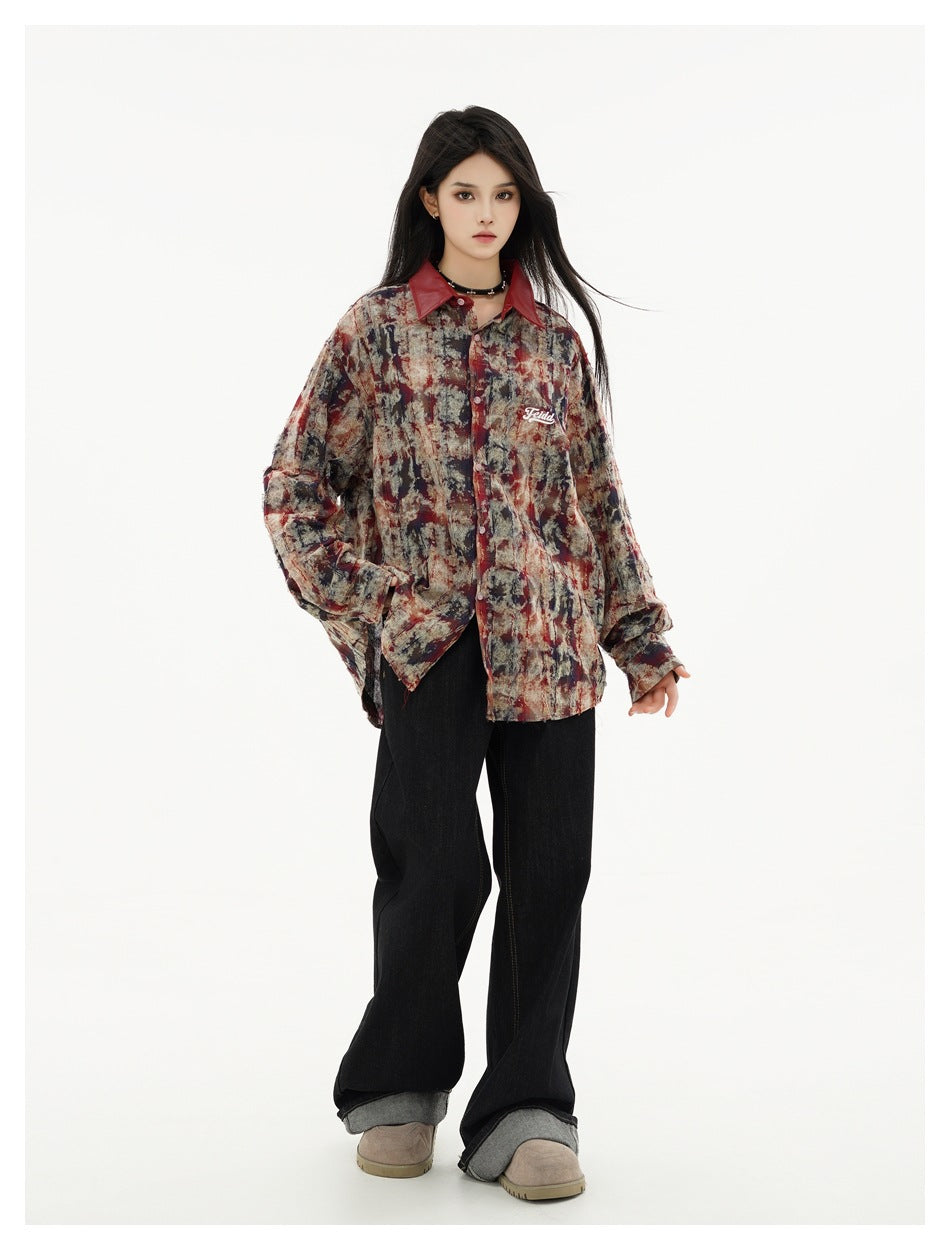 Front view of a model in an oversized red-collar abstract-print shirt and black wide-leg jeans.