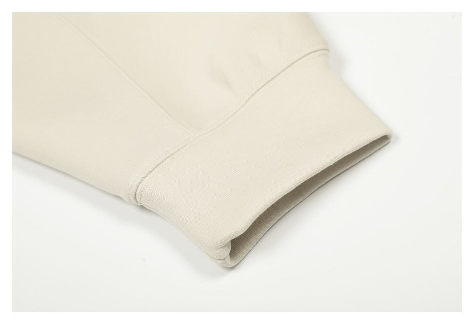 Close-up of the cream hoodie’s ribbed sleeve cuff and stitching.