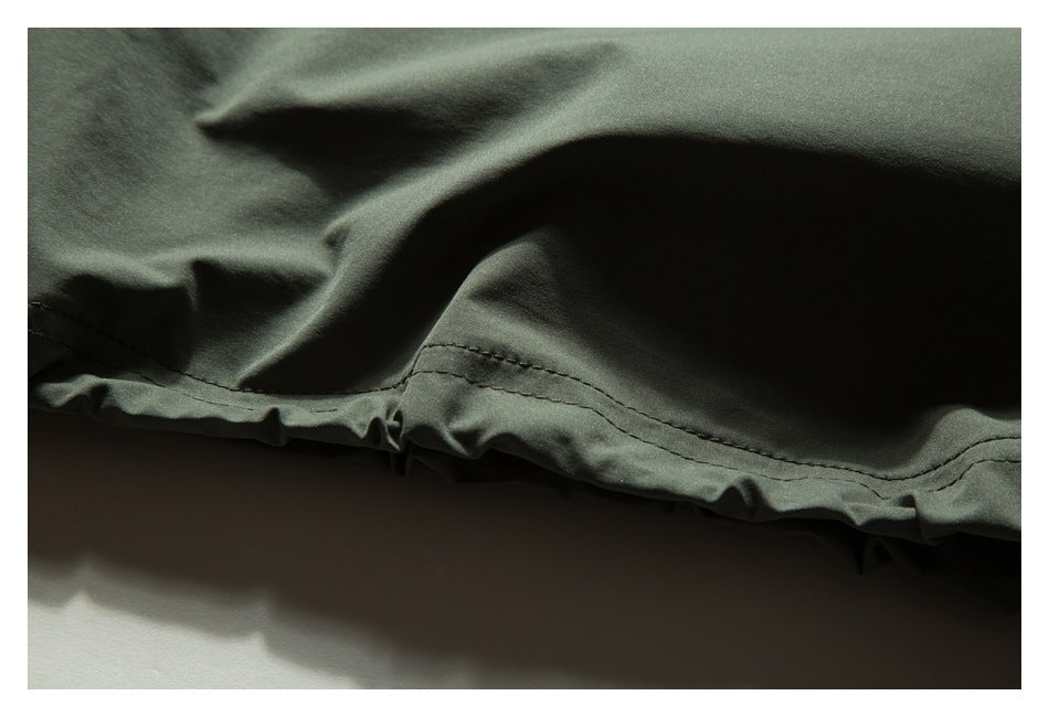 Close-up of a stitched hem on gathered dark olive-green fabric.