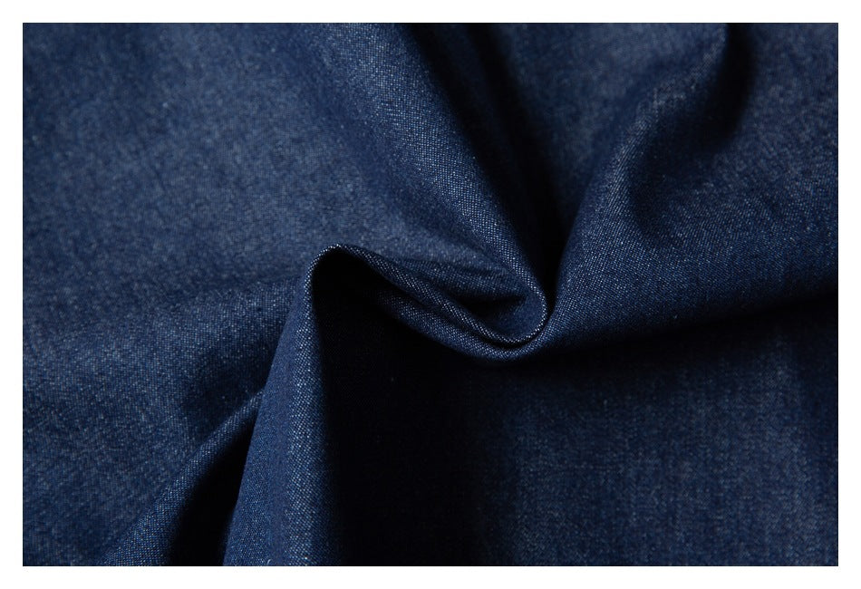 Close-up of dark indigo-blue fabric gathered into a soft fold, showing its fine woven texture.