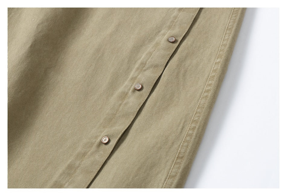 Close-up of the khaki trousers' button fastening and stitched side seam.