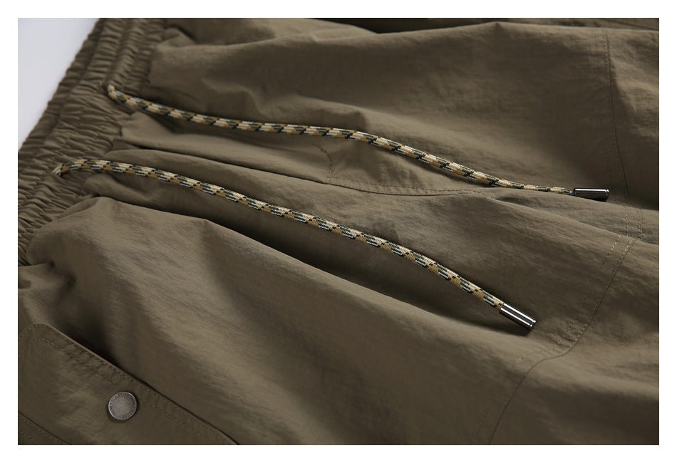 Close-up of patterned drawcords with metal tips above the pants' front pocket area.