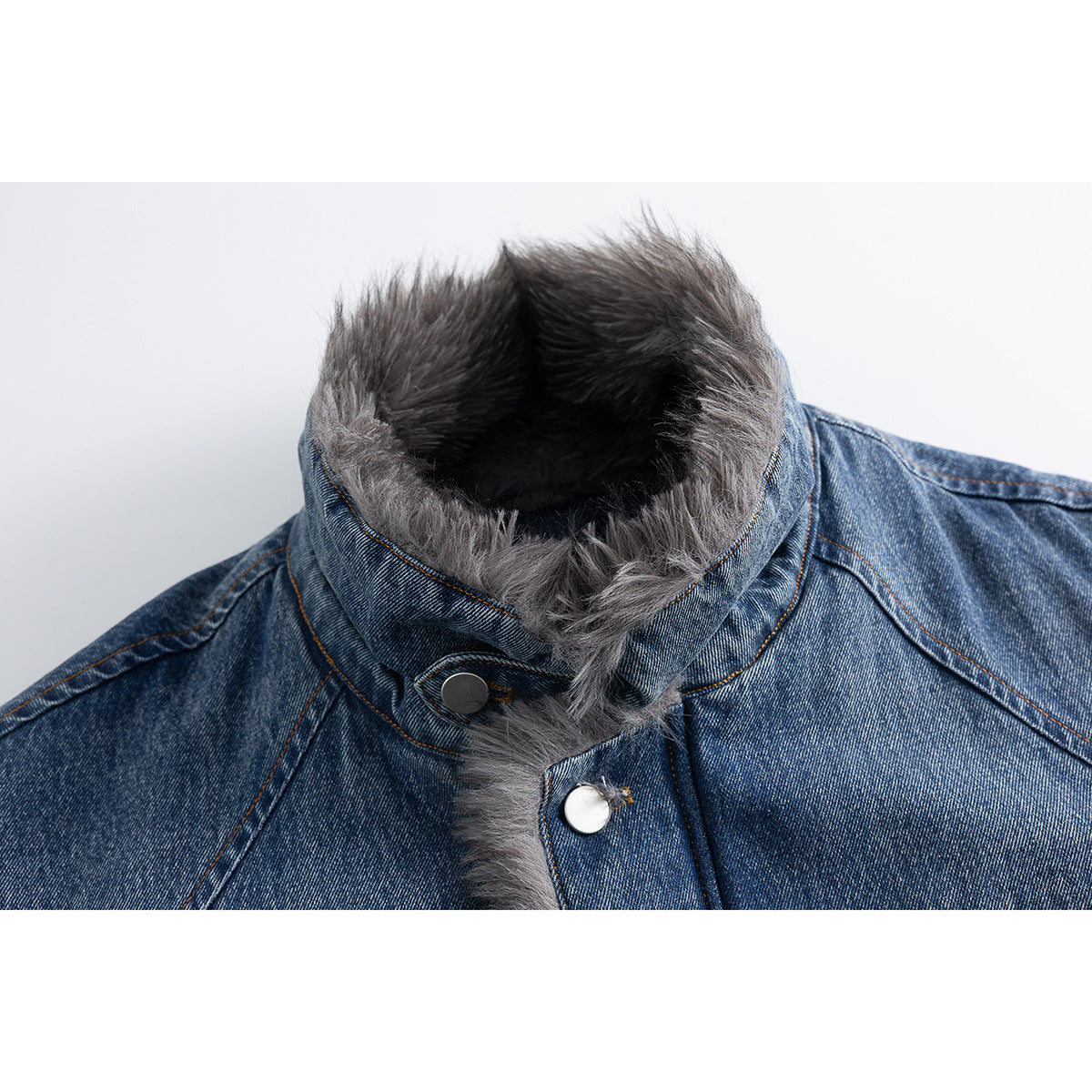 Close-up of a blue denim jacket's tall collar with gray faux-fur trim and silver snap buttons.