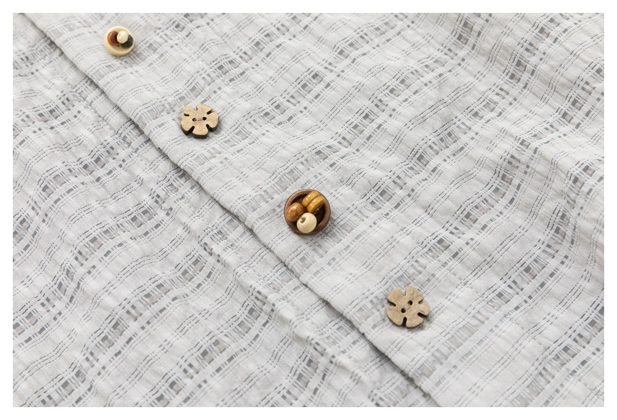 Close-up of a light gray checked shirt placket and its decorative wood-tone buttons.