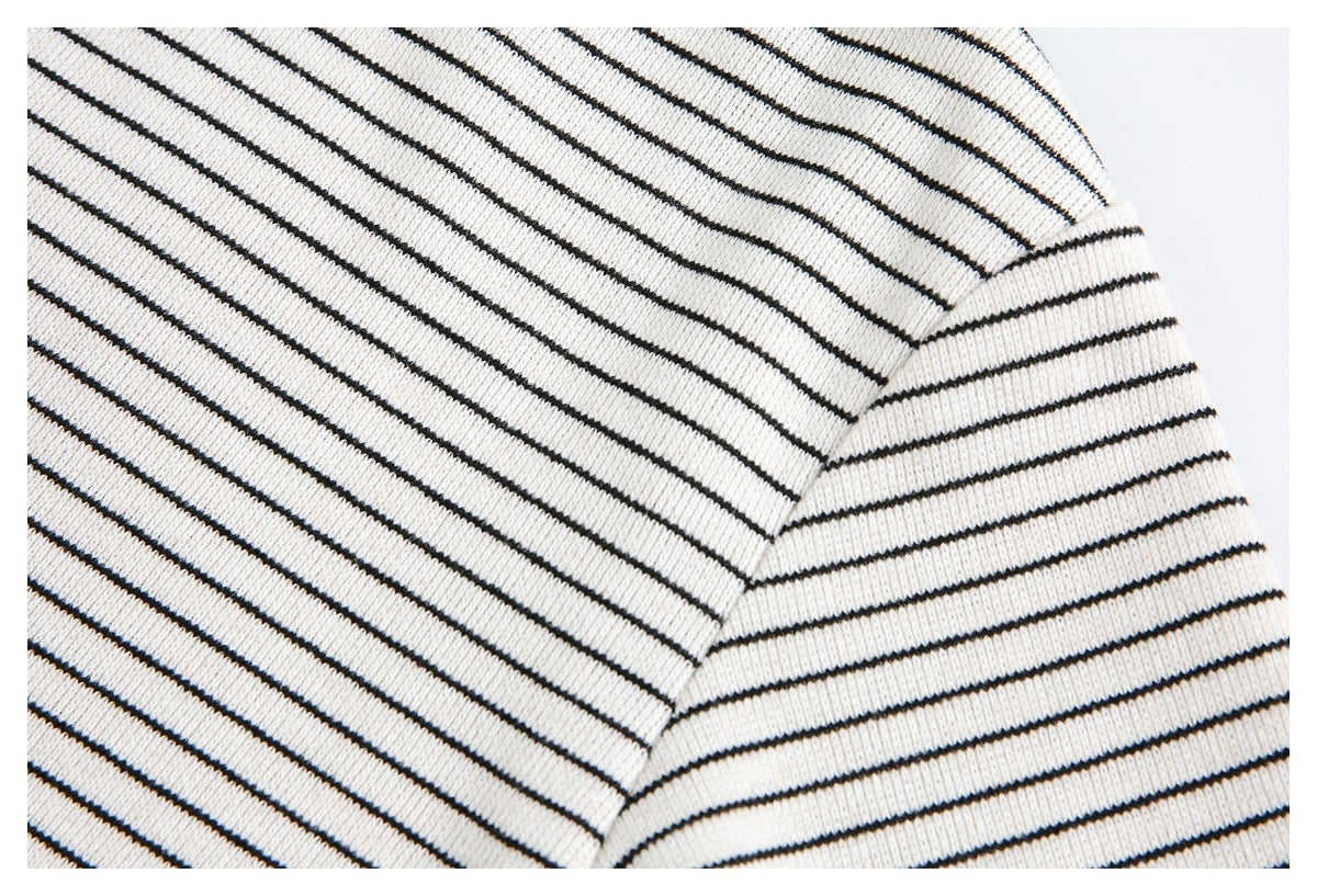Close-up of a striped knit top's shoulder and sleeve seam in cream and black.