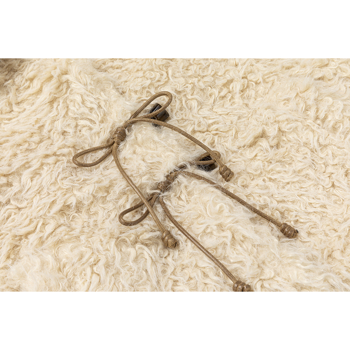 Brown cord toggles and loops shown against curly cream-colored pile fabric.