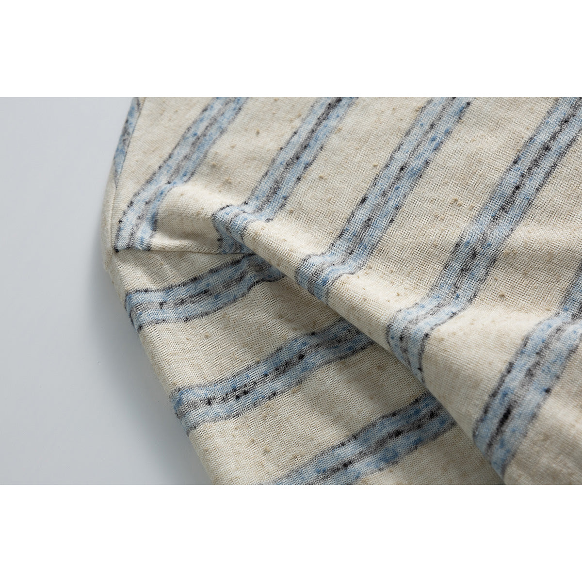 Close-up of the cream top's mottled blue and gray stripe pattern and folded fabric.