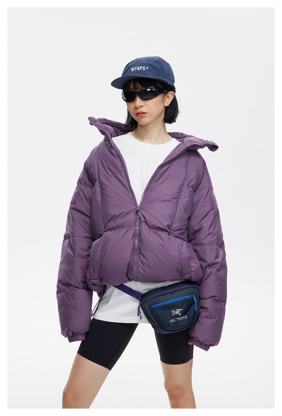 Model wearing an open plum-purple quilted puffer jacket with a high collar and front zip.